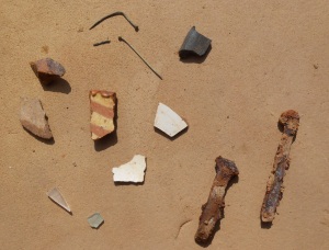 Artifacts from the corner I excavated, including ceramics (center), glass (bottom left), straight pins (top left), burnt polished bone (top right), and nails (bottom right).